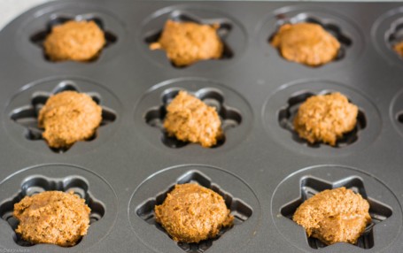 Gingerbread madeleine batter spooned into snowflake shapes cookie pan